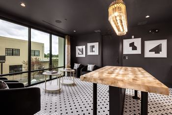 a large wooden table in a room with black and white tile and a large window